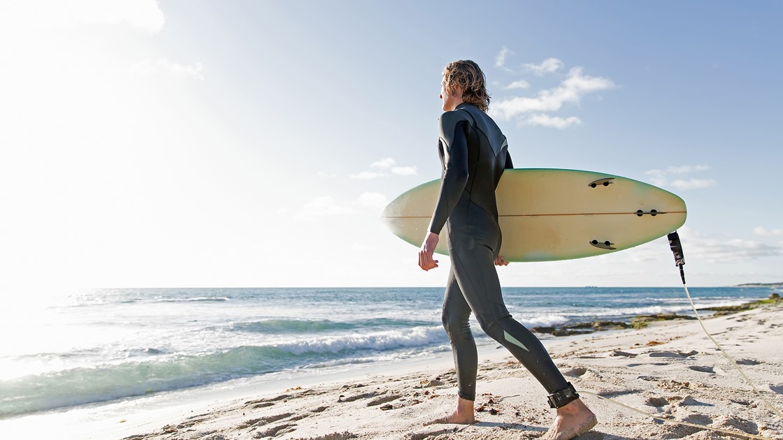 A surfer with his surfboard at the beach